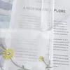A close-up view of a sheer curtain with embroidered flowers and text printed on translucent material. Produktbild-Vorschau