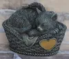 A sleeping cat figurine with angel wings in a basket, placed on a brick surface. Anteprima dell’immagine prodotto