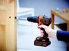 A person is using a Black & Decker cordless drill to drill a hole in a wooden door. Anteprima dell’immagine prodotto