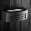 A black outdoor wall lamp mounted on a dark wooden wall. Anteprima dell’immagine prodotto
