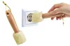 A hand is using a cleaning tool to clean an electrical outlet. Produktbild-Vorschau