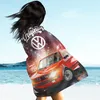 A person on a beach is wrapped in a blanket with a car graphic. Produktbild-Vorschau