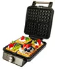 An open waffle maker with four waffles topped with whipped cream and berries. Podgląd zdjęcia produktu