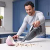 A man is cleaning a kitchen counter with a handheld vacuum cleaner. Anteprima dell’immagine prodotto