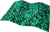 A textured cushion with a repeating pattern of green and black elements, shown from a slightly elevated angle. Produktbild-Vorschau