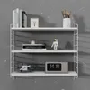 A white modular wall shelf unit with various decorative items and books on it, set against a speckled gray wall. Voir les images du produit