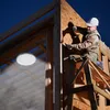 A construction worker is installing a high bay LED light on the frame of a building. Produktbild-Vorschau