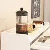 A white shelf with a French press, a mug, and some pastries. Podgląd zdjęcia produktu