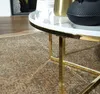 Detailansicht der runden Tischplatte in Marmoroptik Weiß mit goldenem Metallgestell von der Seite. Produktbild-Vorschau