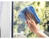 A hand is cleaning a window with a blue microfiber cloth. Náhled obrázku produktu