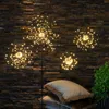 A decorative LED light display resembling fireworks is set against a stone wall, with pillows and greenery in the foreground. Produktbild-Vorschau