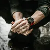 A person's hands are shown with a watch on the wrist, with water splashing around. Produktbild-Vorschau
