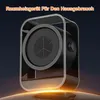 A black and gray compact space heater with a clear plastic frame, set against a dark background with a warm orange glow at the bottom. Produktbild-Vorschau