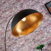 A close-up of a black arc floor lamp with a gold interior shade, set against a brick wall. Produktbild-Vorschau
