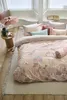 A bedroom scene with a bed dressed in floral bedding, a side table with decorative items, and a window in the background. Produktbild-Vorschau