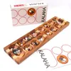 Kalaha-Steinchenspiel mit Verpackung und Anleitung; Holzbrett mit Mulden und farbigen Bohnensteinen dekorativ arrangiert. Produktbild-Vorschau