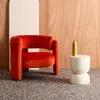 A red velvet armchair is placed next to a white side table with a yellow vase on it, against a wooden wall. Anteprima dell’immagine prodotto