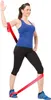 A woman is demonstrating an exercise using a red resistance band. Produktbild-Vorschau