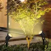 Two black LED garden lights illuminate a small tree and surrounding rocks and paving stones at night. Náhled obrázku produktu