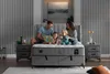 A family is reading a book on a bed in a bedroom. Produktbild-Vorschau