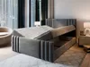 A modern bedroom with a grey upholstered bed frame, open to reveal storage space underneath the mattress. A bedside table with a lamp and books is visible to the right. Produktbild-Vorschau