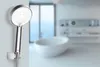 A shower head is mounted on a wall in a modern bathroom with a bathtub in the background. Náhľad obrázku produktu