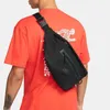 A person wearing a black Nike hip pack over an orange t-shirt. Náhľad obrázku produktu