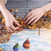 Hands assembling a jigsaw puzzle on a puzzle mat. Anteprima dell’immagine prodotto