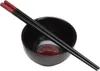 A black ceramic bowl with a red design inside, and black chopsticks with red tips resting on top. Náhled obrázku produktu