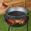 A cast iron pan is placed on a grill over hot coals. Produktbild-Vorschau