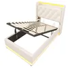 A white upholstered bed frame with the mattress support mechanism lifted to reveal storage space underneath. Yellow LED lighting is visible along the headboard and base. Náhľad obrázku produktu