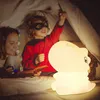 A mother and child are playing in a tent with a dinosaur-shaped night light. Voir les images du produit