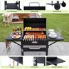 A charcoal grill with food being cooked, surrounded by accessories and outdoor setting elements. Anteprima dell’immagine prodotto