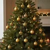 A close-up view of a decorated Christmas tree with gold ornaments and lights. Voir les images du produit