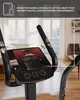Close-up of an exercise bike's console with a tablet displaying a motivational screen, set in a home environment. Podgląd zdjęcia produktu