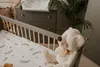 A nursery setting with a crib, changing table, and a teddy bear. Náhled obrázku produktu