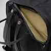 A close-up view of an open zipper pocket on a black backpack, revealing a tan interior. Produktbild-Vorschau