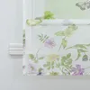 A close-up view of a floral patterned roller blind hanging on a window. Produktbild-Vorschau