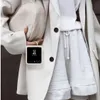 A person wearing a cream blazer and grey shorts, holding a cream handbag and a white phone case with a phone inside. Anteprima dell’immagine prodotto