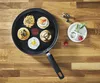 A frying pan with several small pancakes topped with various ingredients, arranged on a wooden surface. Voir les images du produit