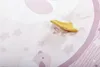 A close-up of a pink baby playmat with stars and a butterfly pattern, with a yellow toy star resting on it. Náhled obrázku produktu