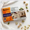 Kandylas Halva mit Pistazien 400 g Verpackung auf weißem Stoff mit verstreuten Pistazien Produktbild-Vorschau