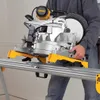 A person is holding a DeWALT miter saw on a stand. Produktbild-Vorschau