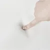 A finger pressing into a white, soft surface. Produktbild-Vorschau