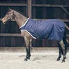 A horse wearing a navy blue blanket stands in a stable. Produktbild-Vorschau