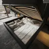 A bed with its storage compartment open, revealing bedding and pillows. The scene is set in a bedroom with a rug and a glimpse of a balcony. Produktbild-Vorschau