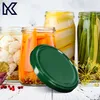 A collection of jars filled with preserved vegetables, with a green lid in the foreground. Podgląd zdjęcia produktu