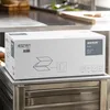 A box of Katrin Plus Z-Z Falthandtücher is placed on a stainless steel surface in what appears to be a commercial kitchen or industrial setting. Náhled obrázku produktu