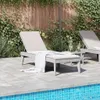 Two lounge chairs by a pool with a wooden fence and greenery in the background. Podgląd zdjęcia produktu