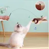 Weiße Katze spielt mit braunem vogelförmigem Stabspielzeug, das von einer Hand gehalten wird, mit schwebenden Noten Náhľad obrázku produktu